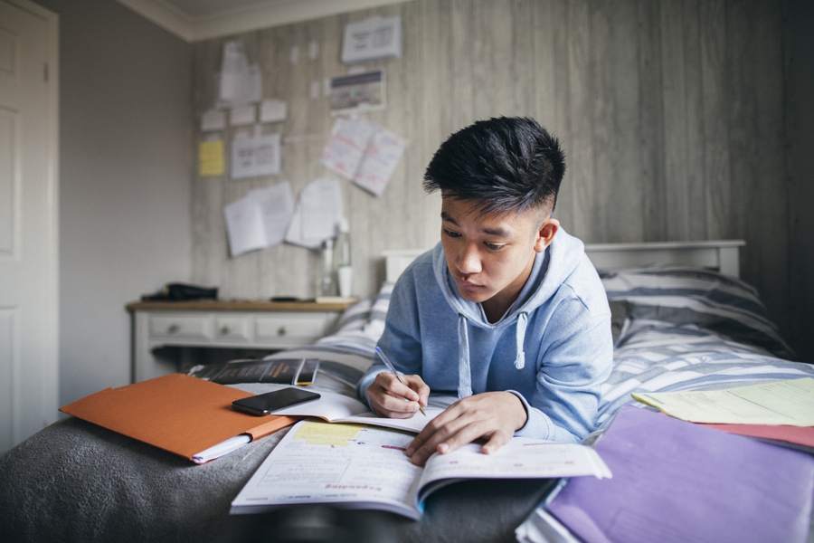 Boy doing high school homework in his room