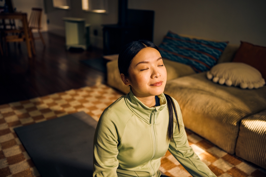 woman facing sunshine with her eyes closed meditating