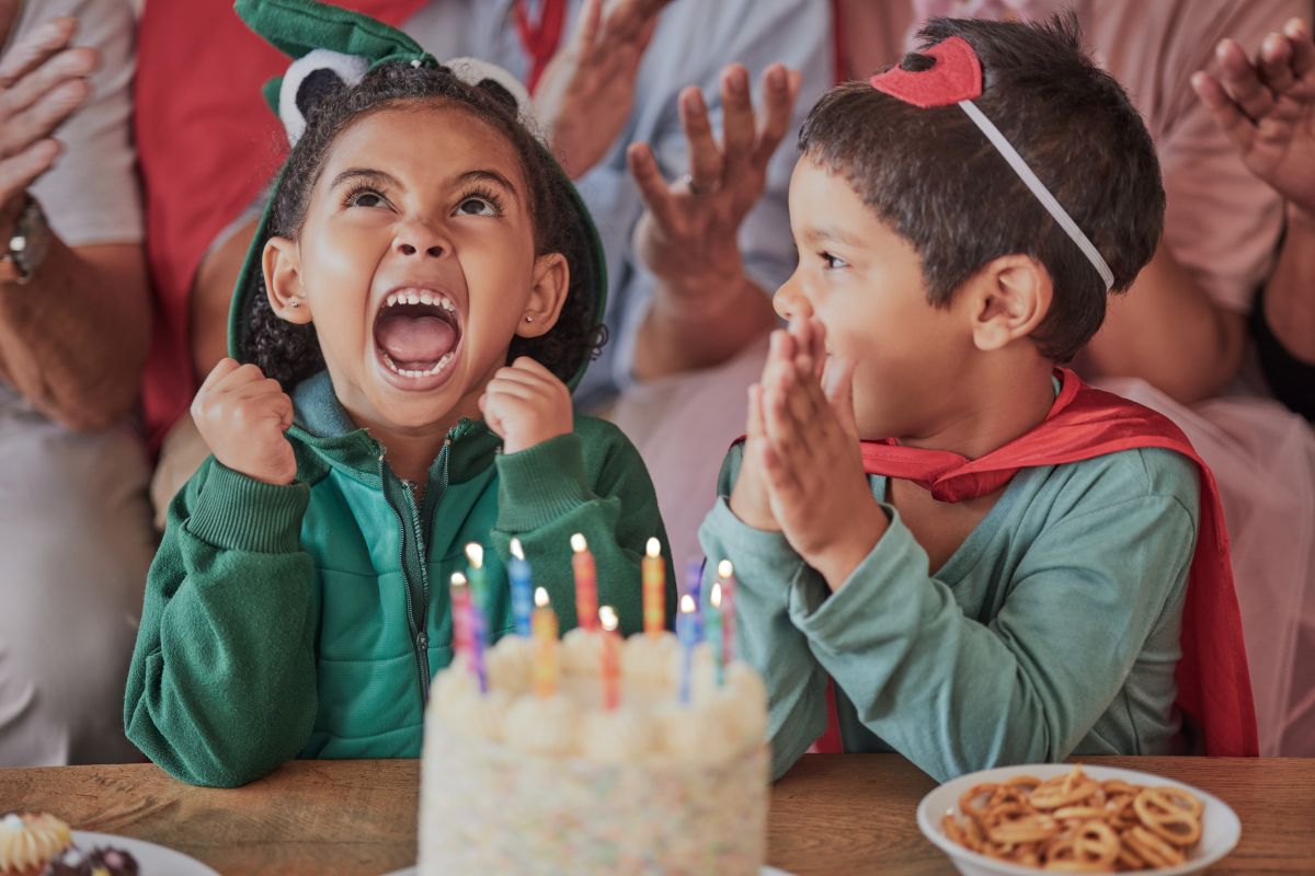An excited child wearing a costume sits in front of cake at a toddler birthday