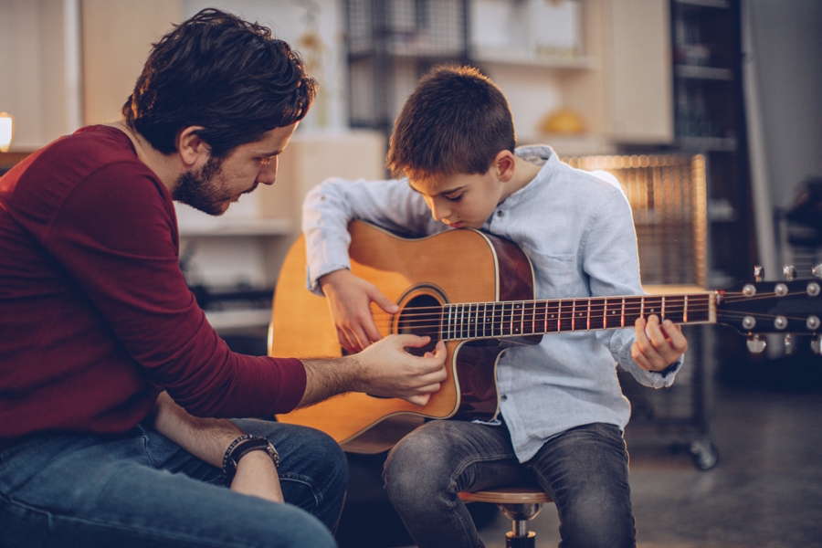 a young boy holding a guitar having a music lesson