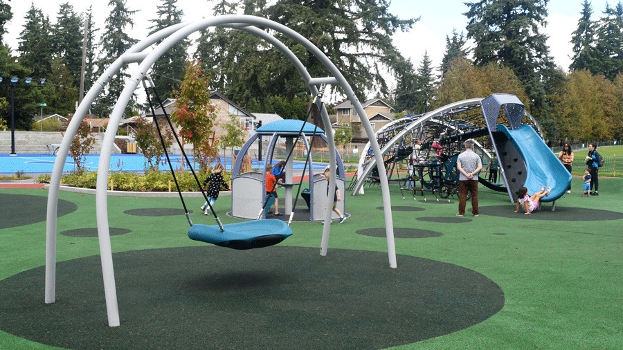 accessible swing and merry-go-round at a new playground in shoreline with kids playing