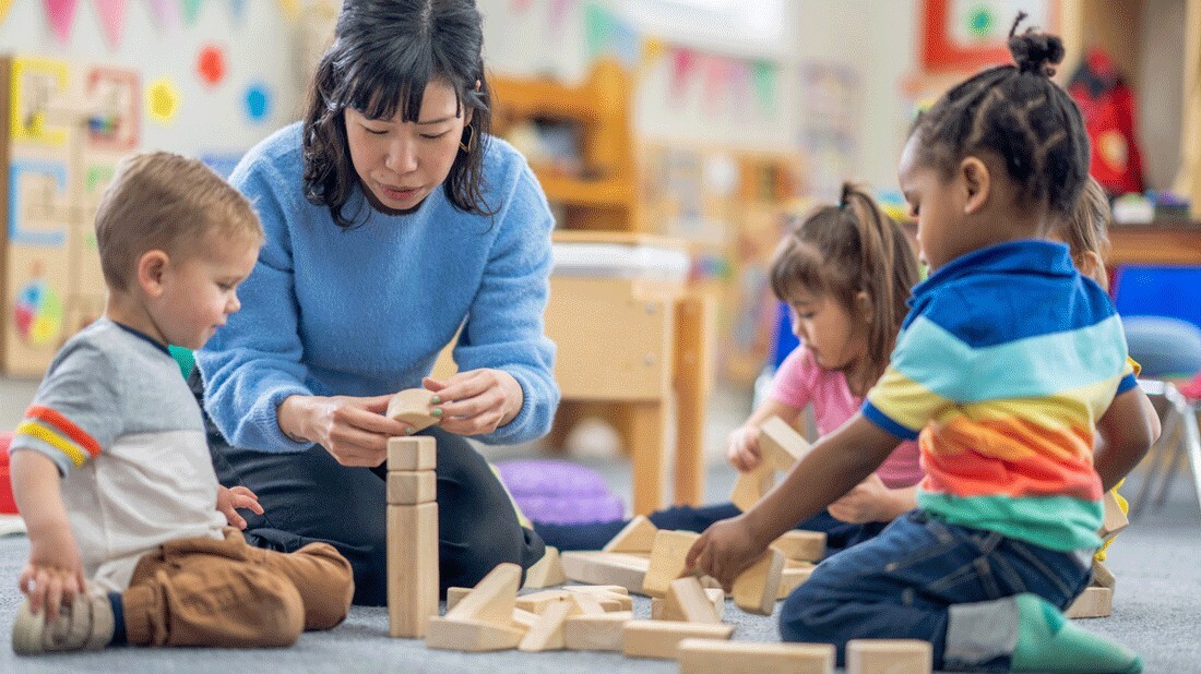 A teacher with kids in a day care playing with blocks