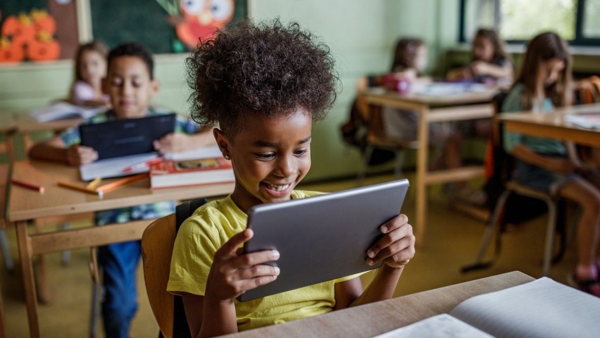 Happy elementary student using touchpad in a class