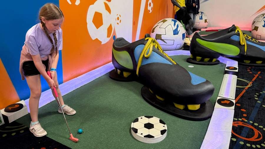 girl playing mini golf on a soccer-themed course at Arena Sports in Mill Creek