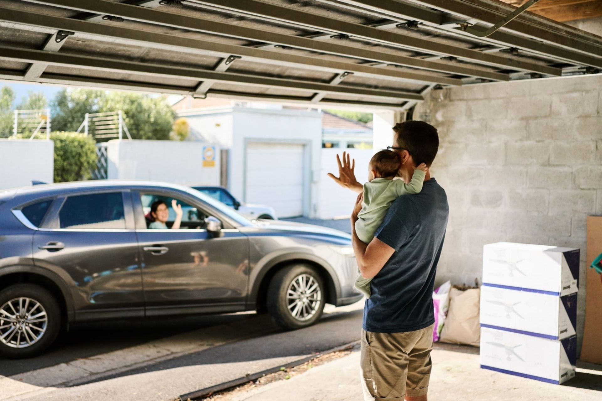 father holding toddler while mother drives away for overnight