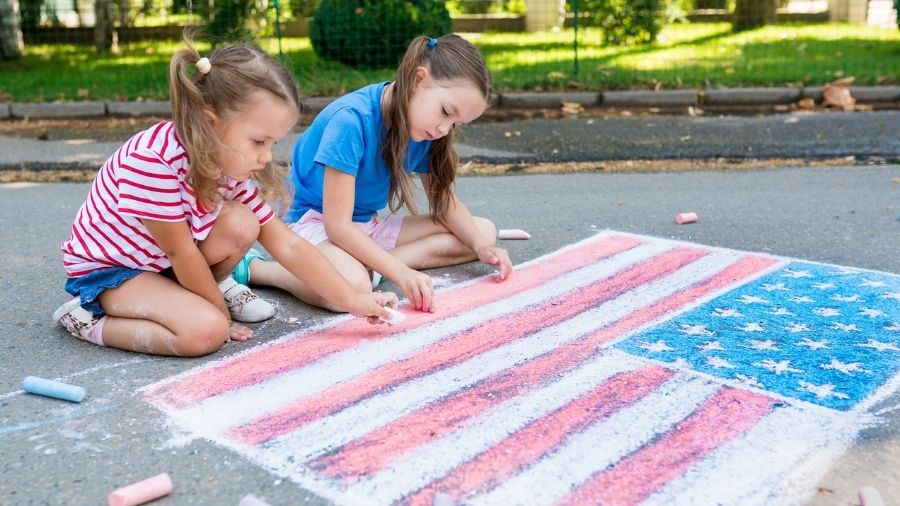 girls drawing American flag with colored chalks on the sidewalk for America's 250th anniversary