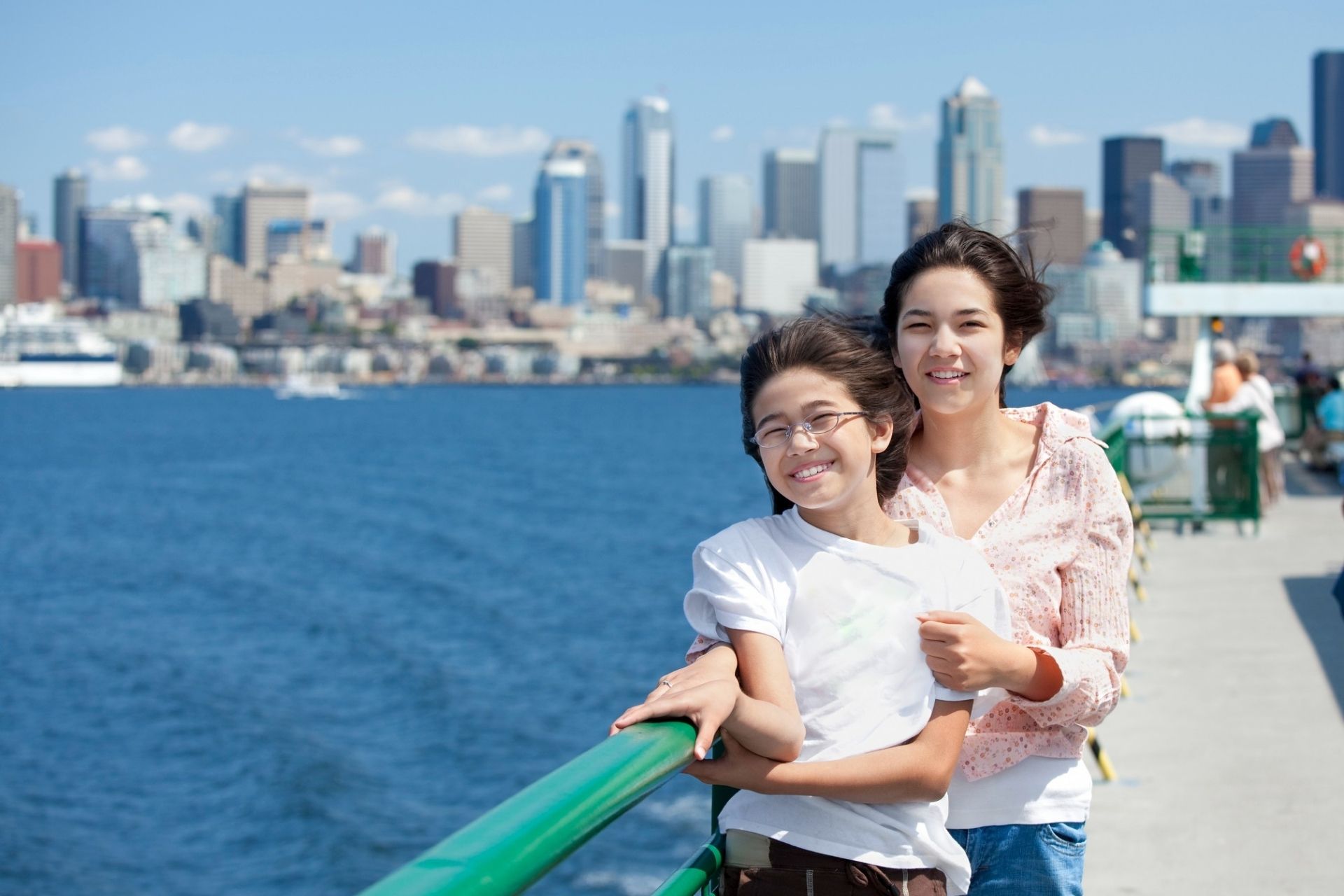 mother and daughter on a ferry with seattle skyline behind