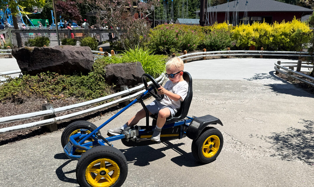 child wearing sunglasses on a pedal tractor at Remlinger Farms, a Seattle-area attraction with season passes