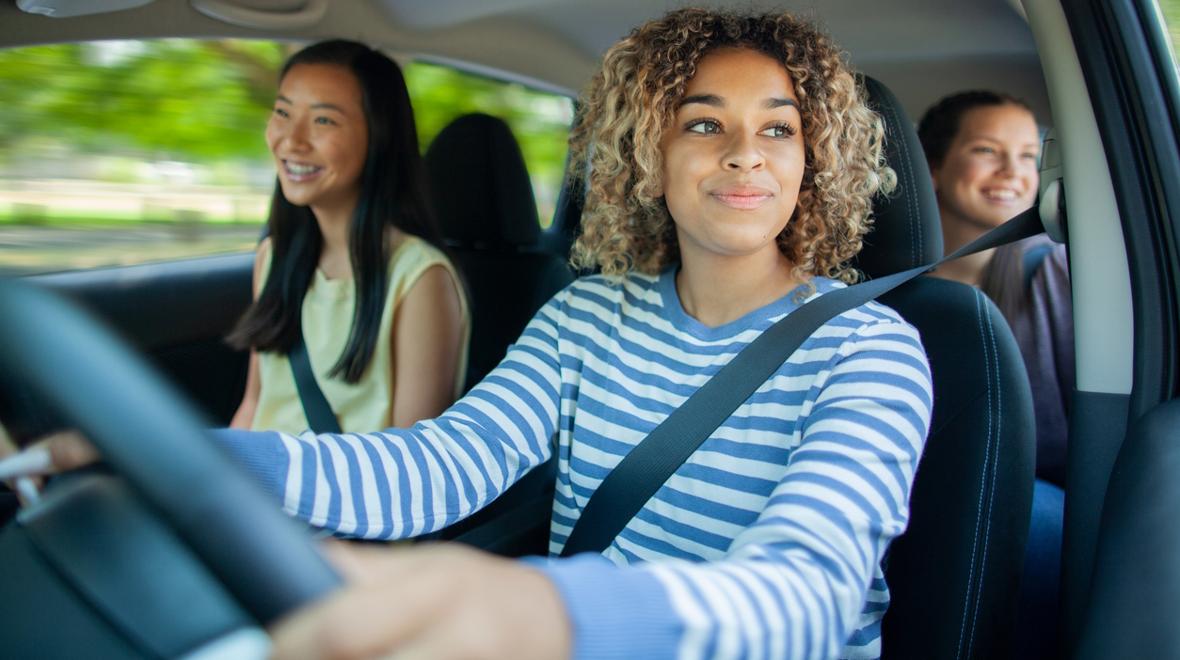 Teen girls driving in a car smiling in summer