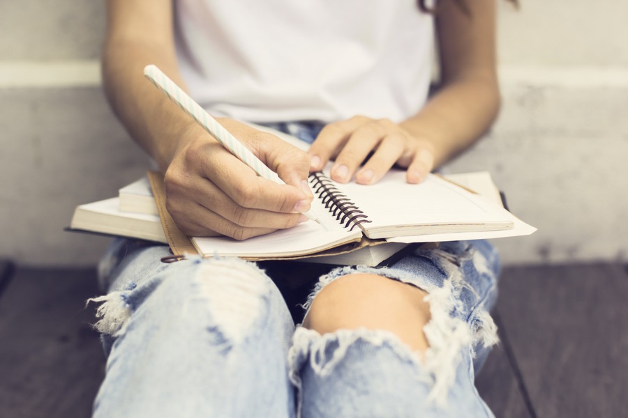 A teenager is journaling, an analog hobby