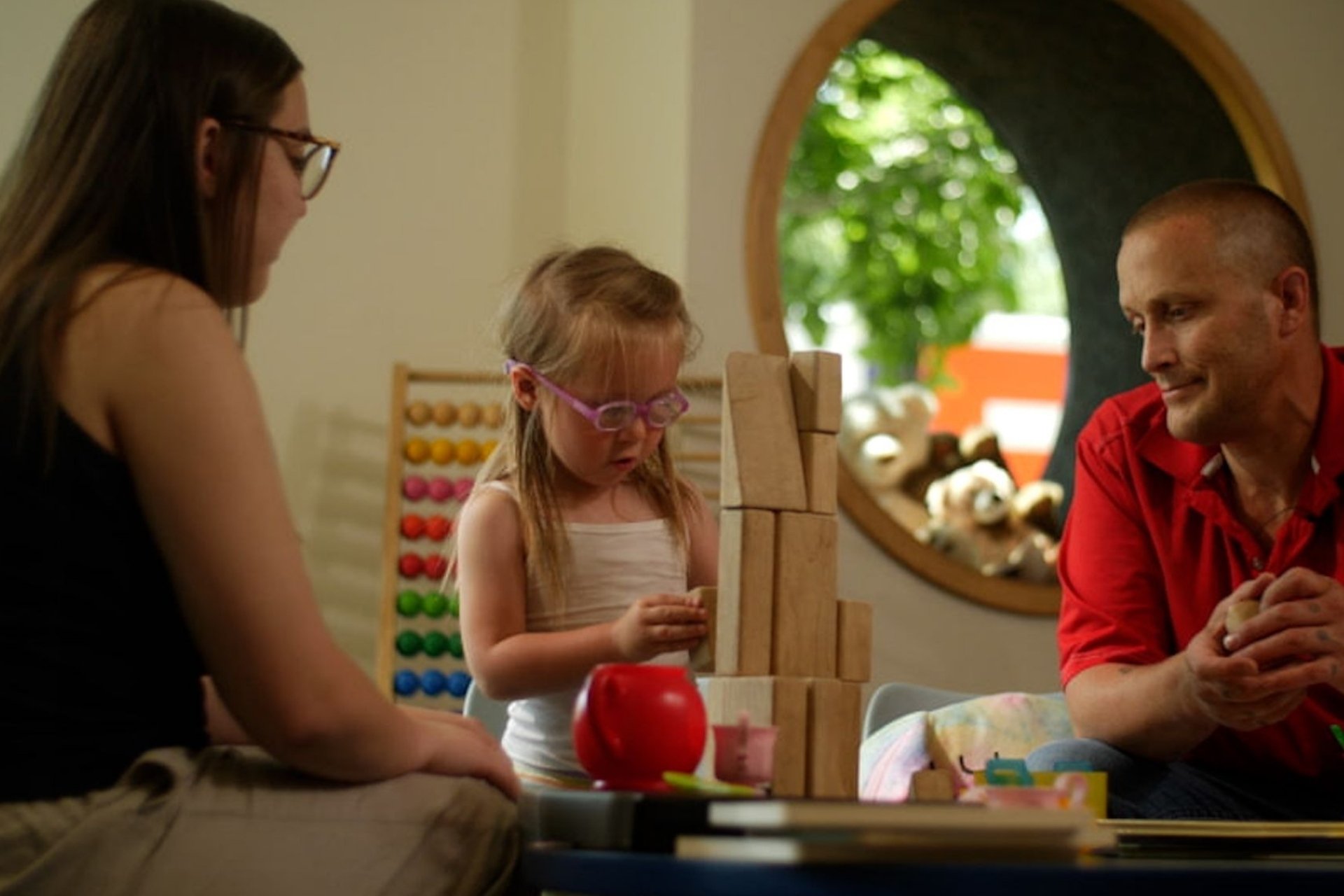 family of three with little girl playing with blocks