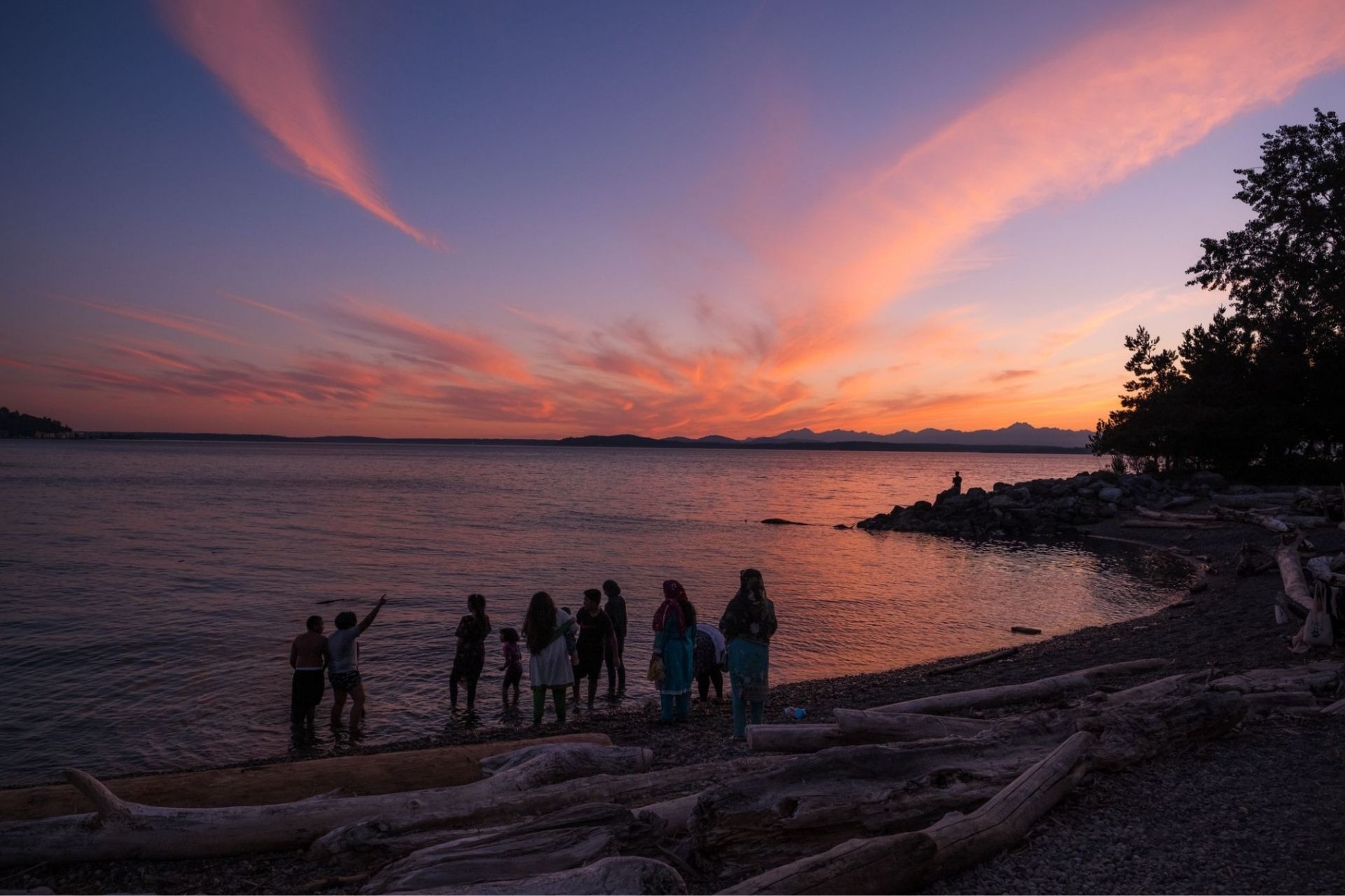a huge family with kids watching the sunset at a beach