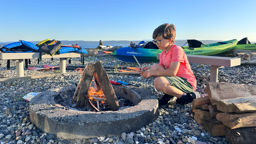 Kid making a fire on the beach during a Camano Island getaway