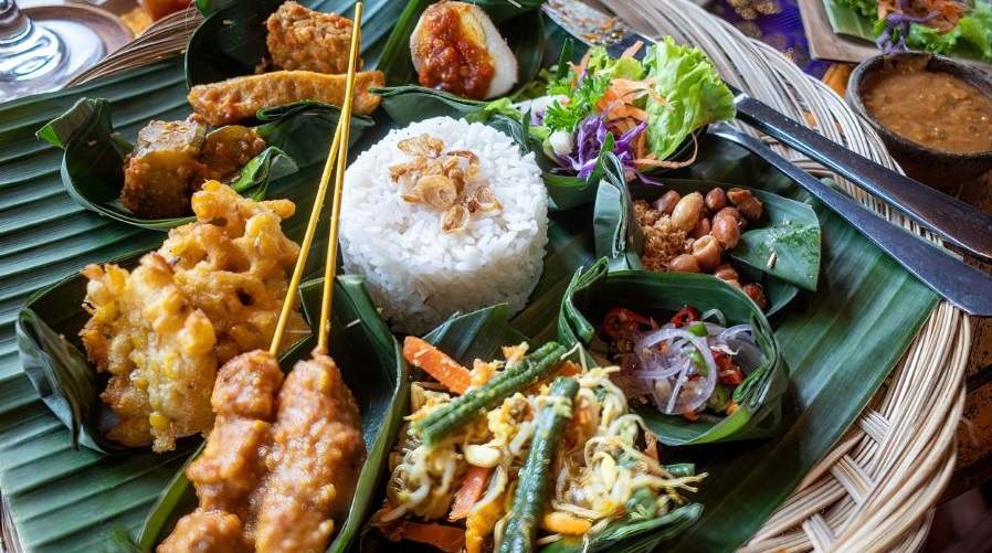 A delicious-looking Indonesian dish with satay, rice and other foods.