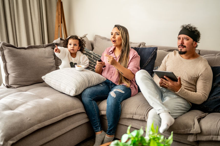 Mom and dad and daughter watching a movie at home and eating a snack