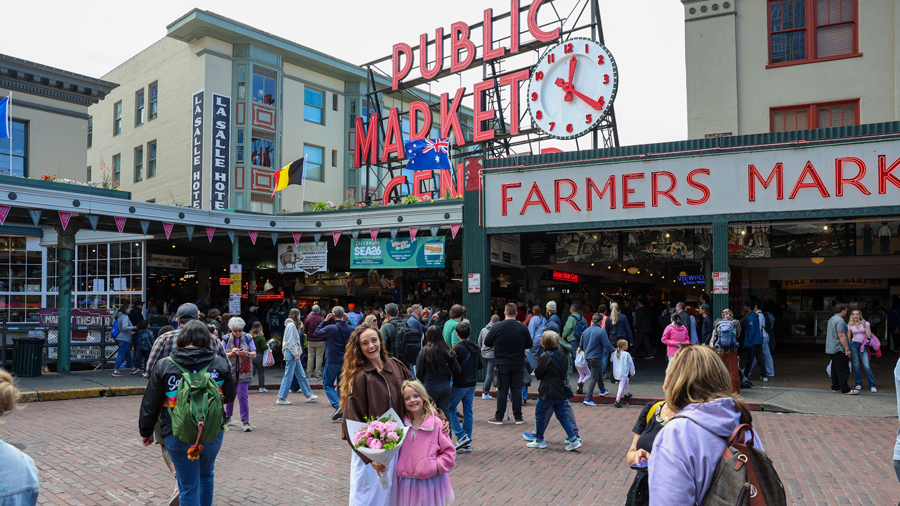 mom and daughter posing in front of the Pike Place Market sign, a top Seattle attraction