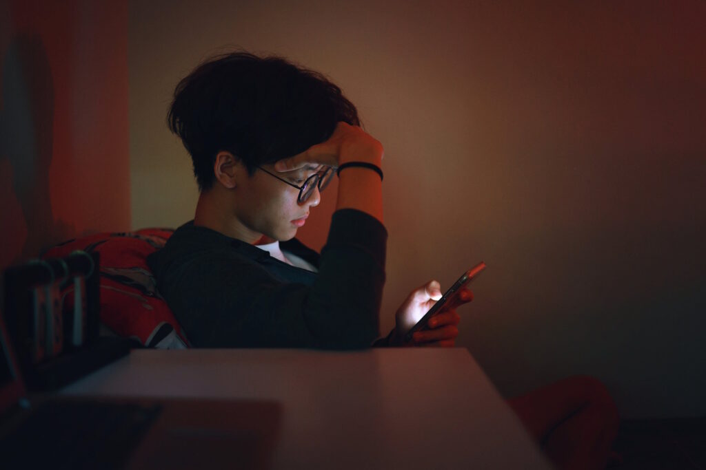Teen boy looking at his phone stressed and anxious who needs help spending time away from his device.