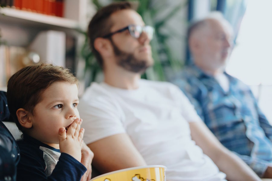 toddler boy watching movie with dad and grandpa