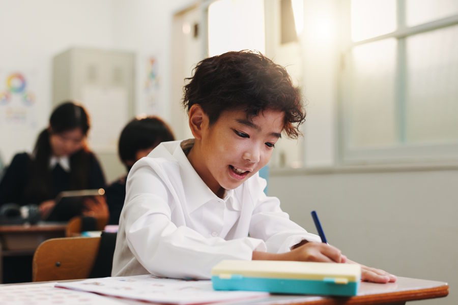 Boy sitting at his desk in middle school doing school work