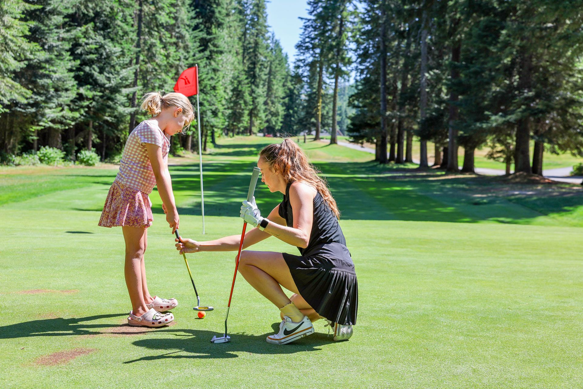 Seattle mom giving golf lessons to child on the course during a round