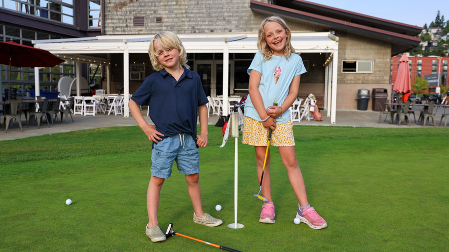 Kids standing outside on golf course holding putters