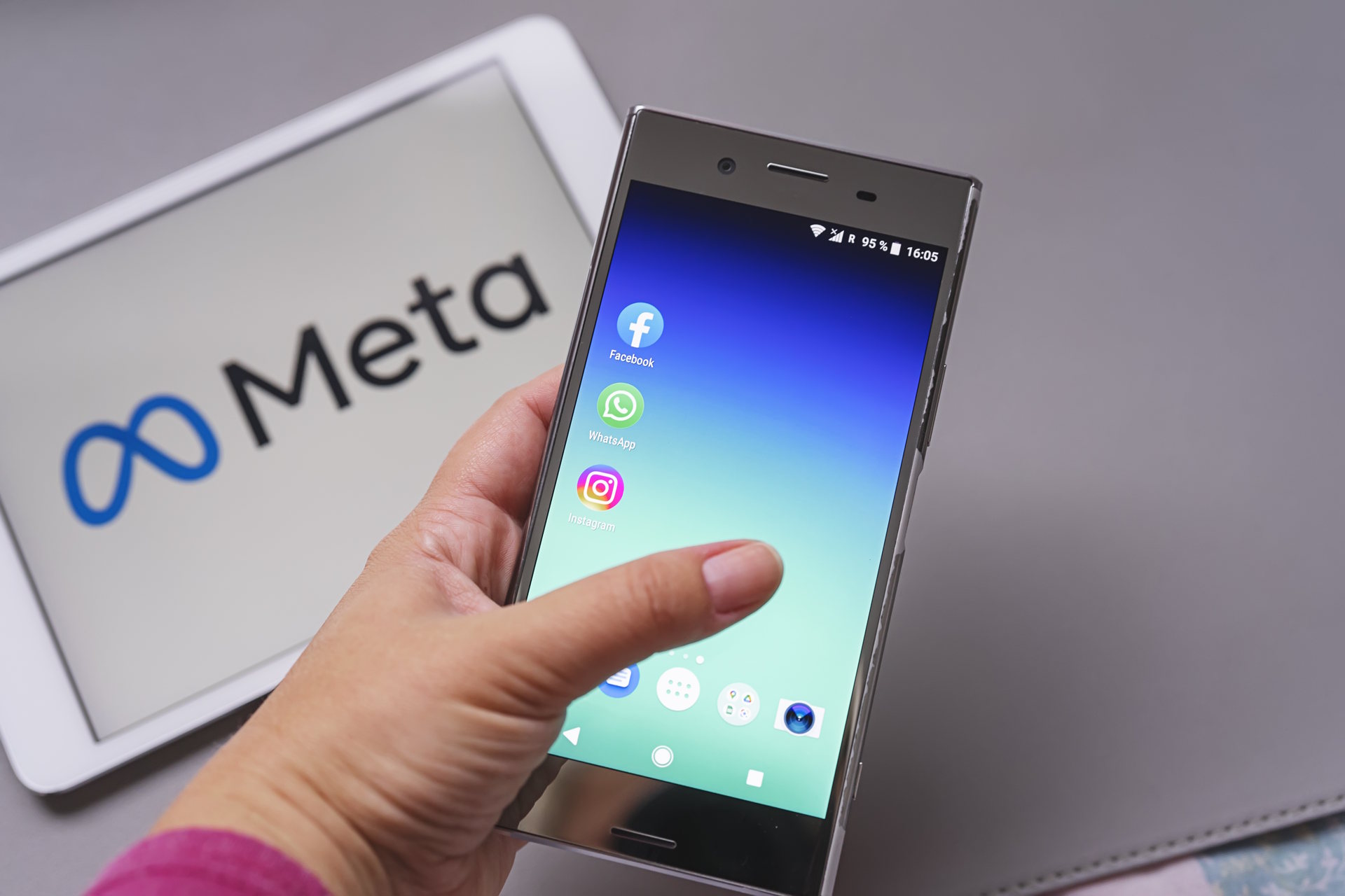 Meta logo on a table and a hand holding a cell phone