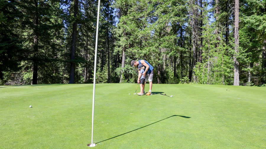 dad golfing with kids on an outdoor course