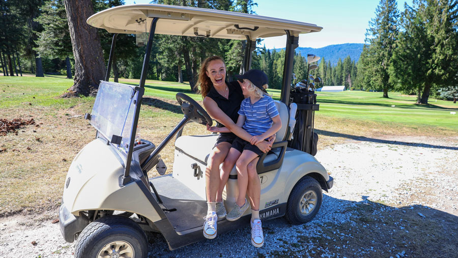 mom and son sitting on golf cart during an outdoor game of golf near Seattle
