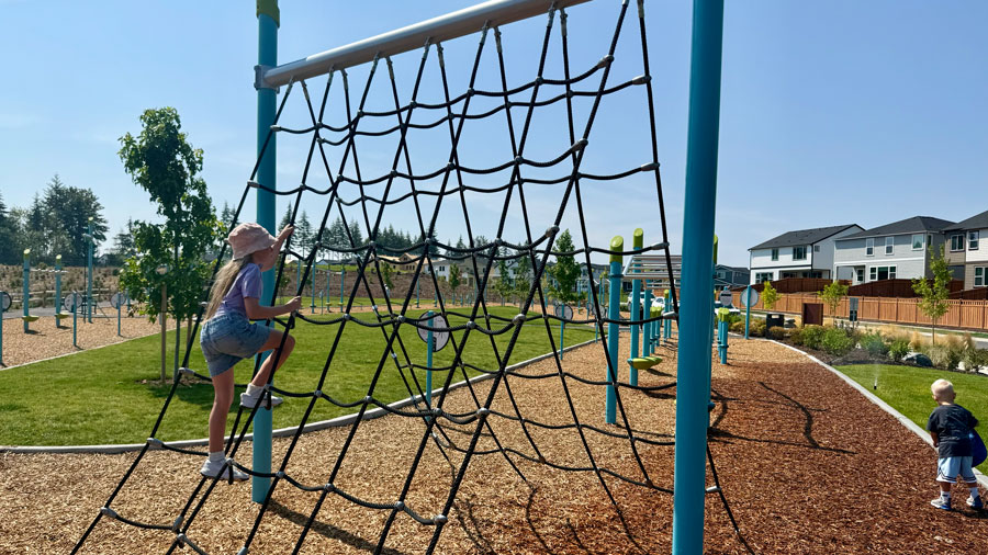 girl climbing over cargo net climber
