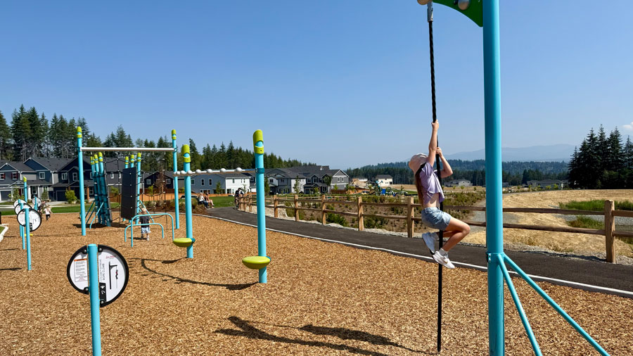 girl climbing rope on the obstacle course at a Tehaleh park