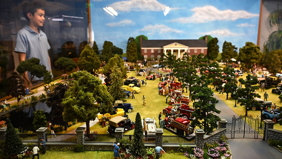 young kid admiring one of the displays in Miniature World, with a full town of miniature buildings and people