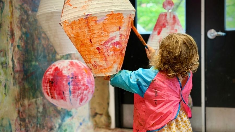 little girl painting a lantern at the play with paint program