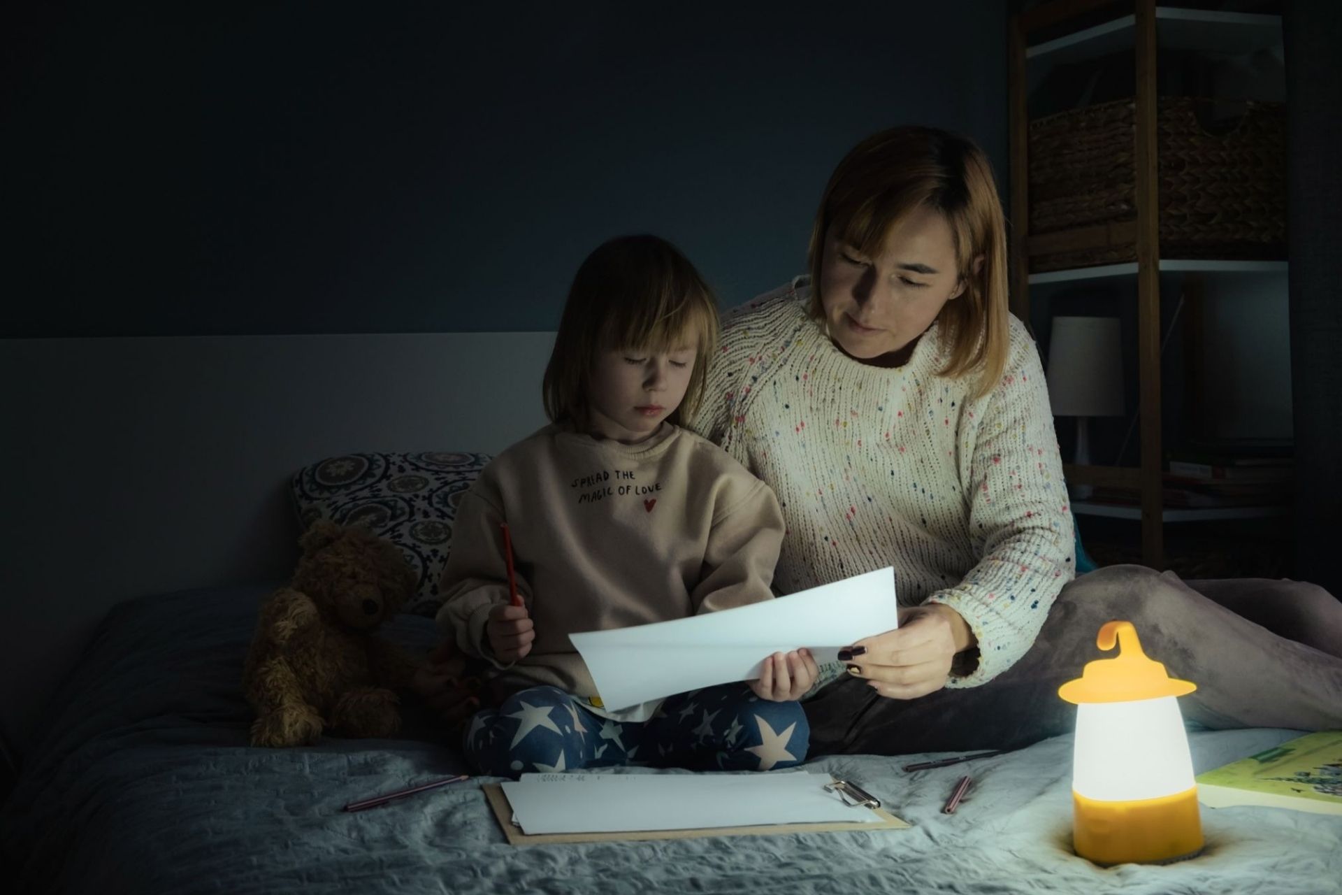mother and daughter working on homework in a dark room with an electric lantern