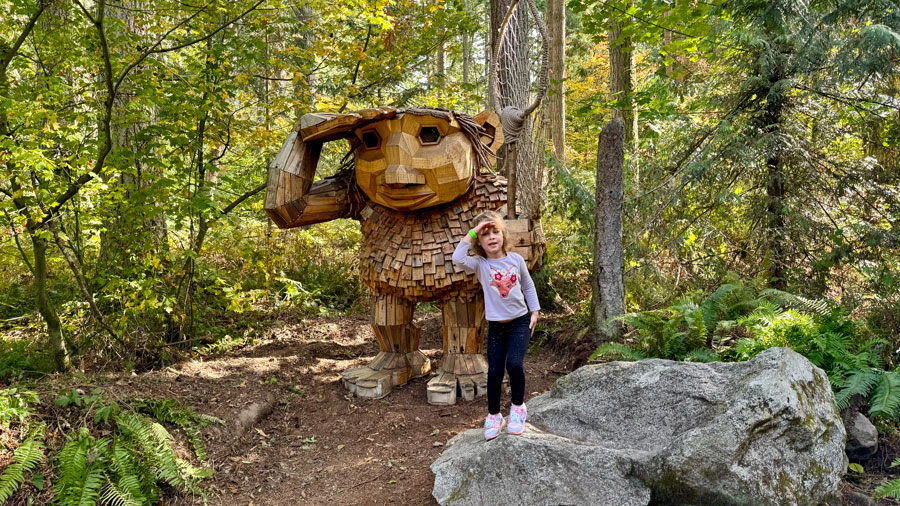 Child posing with Thomas Dambo troll in Washington at NW Trek