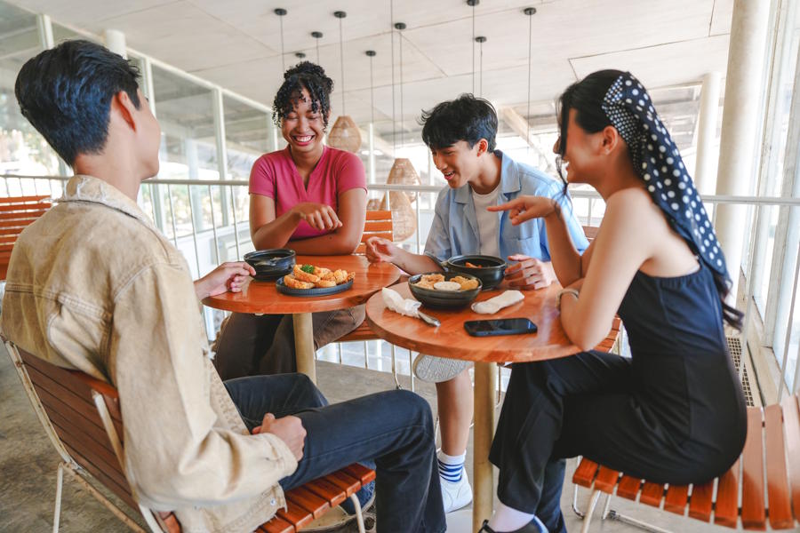 Group of teenagers hanging out and eatting togeher at a cafe