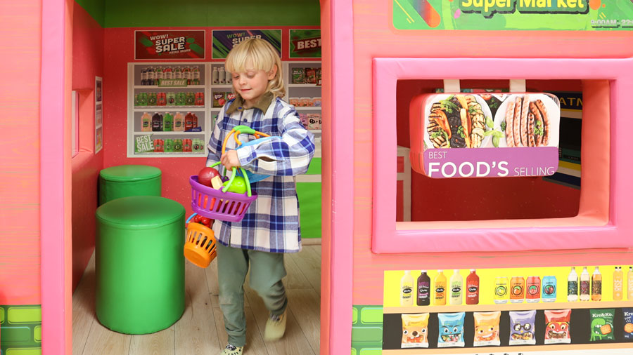 Boy holding groceries playing pretend at Little Pandas Play Cafe