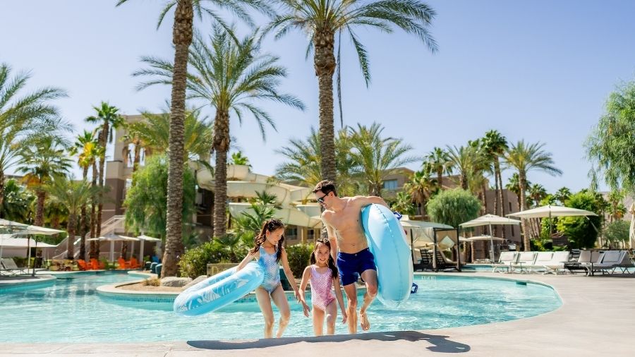 two little girls and their father walking out from the lazy river with their floaties at grand hyatt palm springs