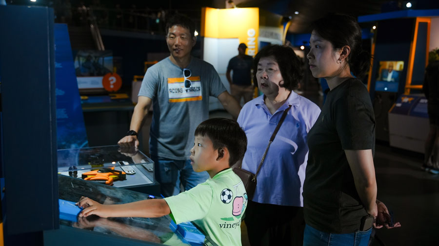 family interacting with the displays at ”Mysteries from the Deep: Exploring Underwater Archaeology” at PacSci