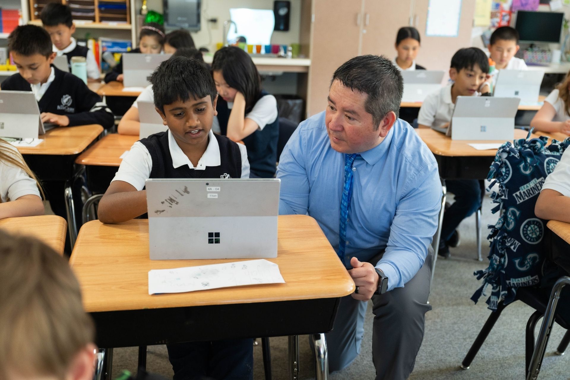 teacher helping a student work on a laptop in a classroom at the bear creek school